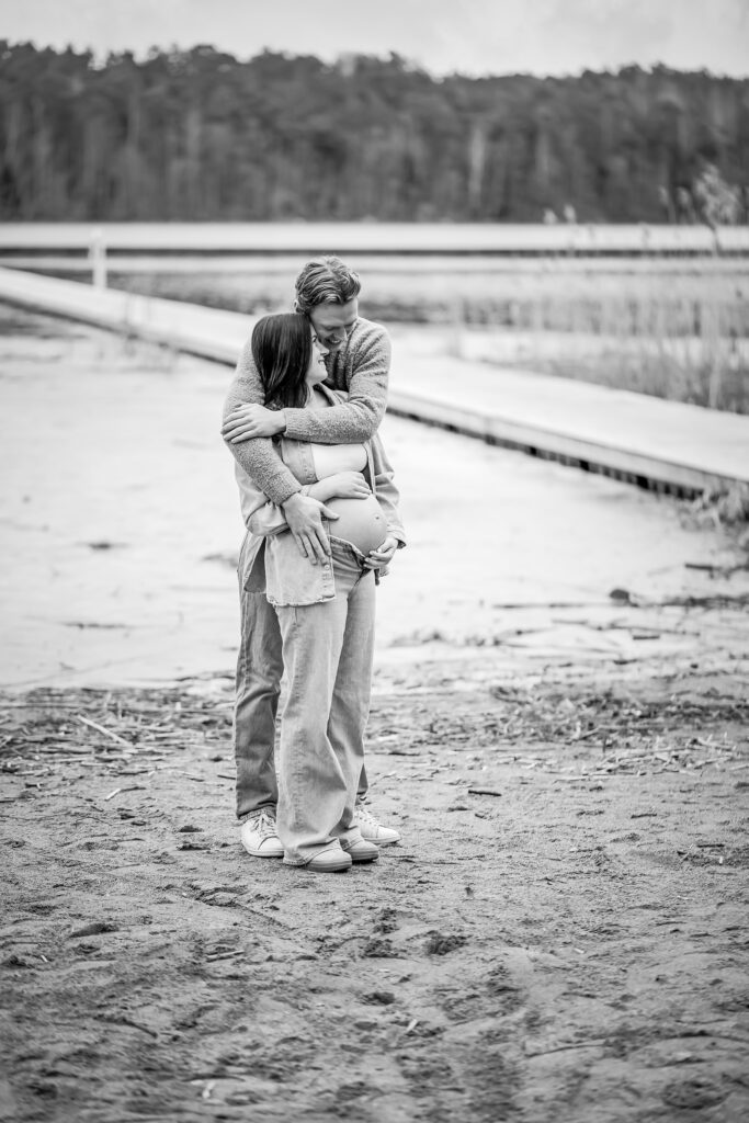Mannen omfamnar kvinnan på en strand - svartvit